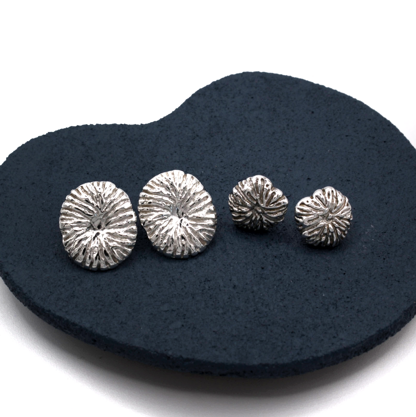 Set of silver textured earrings on a black heart-shaped stand