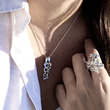 Slim Raíz Necklace, sculptural silver pendant symbolizing resilience and inner strength.
Collar Raíz Slim, colgante escultural en plata que simboliza resiliencia y fuerza interior.