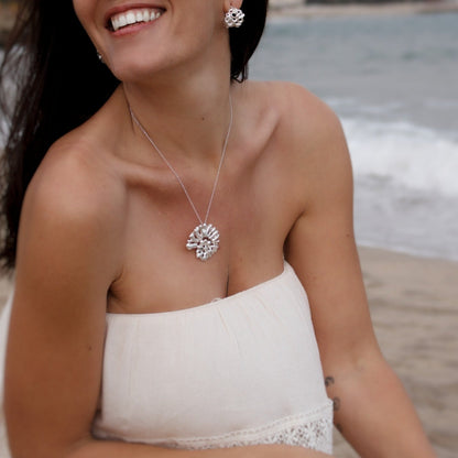 Woman wearing Souvenirs Espiral statement pendant in sterling silver on Mediterranean beach