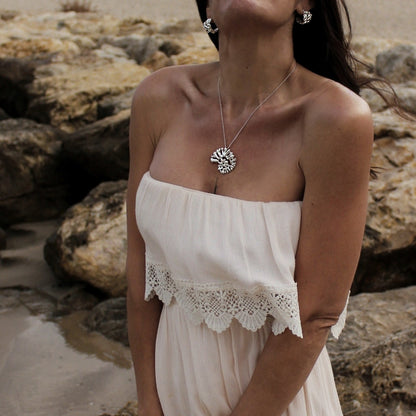 Mediterranean inspired silver statement pendant worn with natural linen dress by the sea