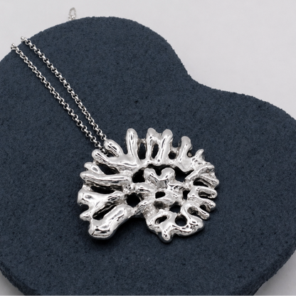 Silver coral-shaped pendant on a chain against a dark gray background