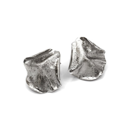 Sculptural folded silver earrings, handcrafted in recycled sterling silver using the lost wax casting technique. Mediterranean-inspired jewelry with organic, wave-like forms and a unique fused silver dust texture. Elegant and sustainable statement earrings for nature and contemporary jewelry lovers, crafted by Naturalesa.