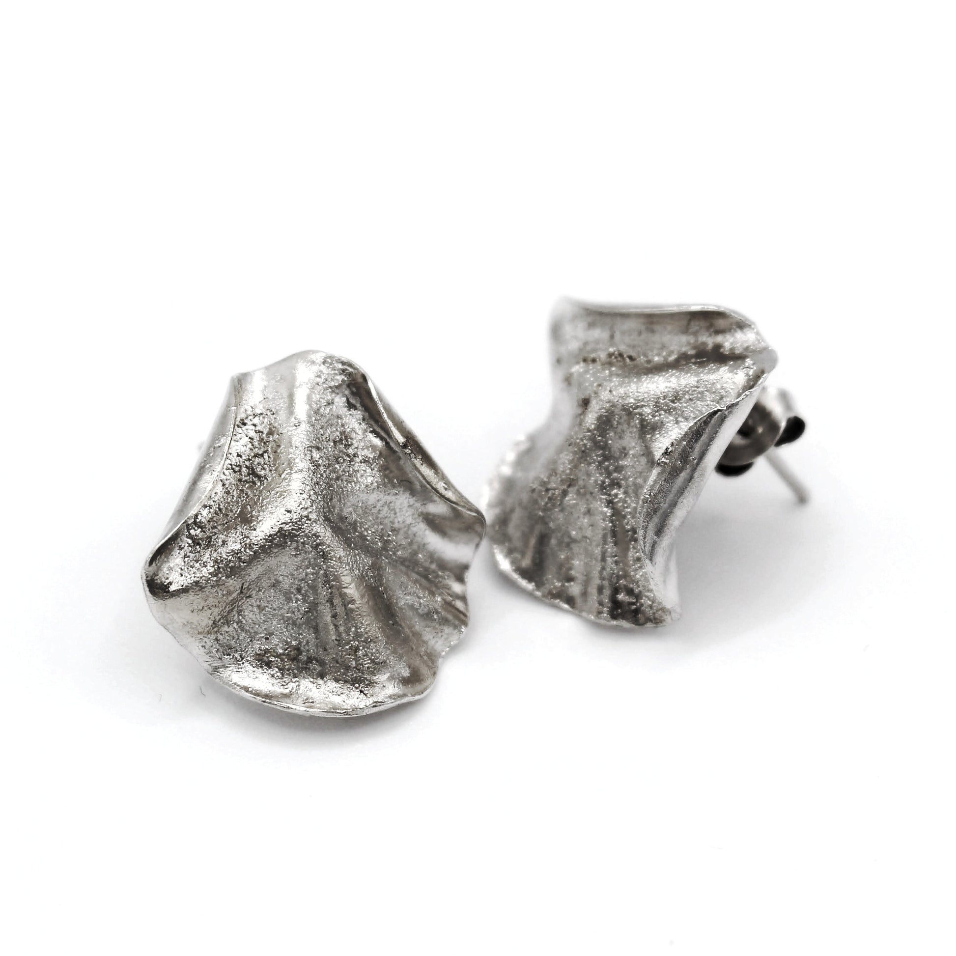 Sculptural folded silver earrings, handcrafted in recycled sterling silver using the lost wax casting technique. Mediterranean inspired jewelry with organic, wave like forms and a unique fused silver dust texture. Elegant and sustainable statement earrings for nature and contemporary jewelry lovers from Naturalesa. 