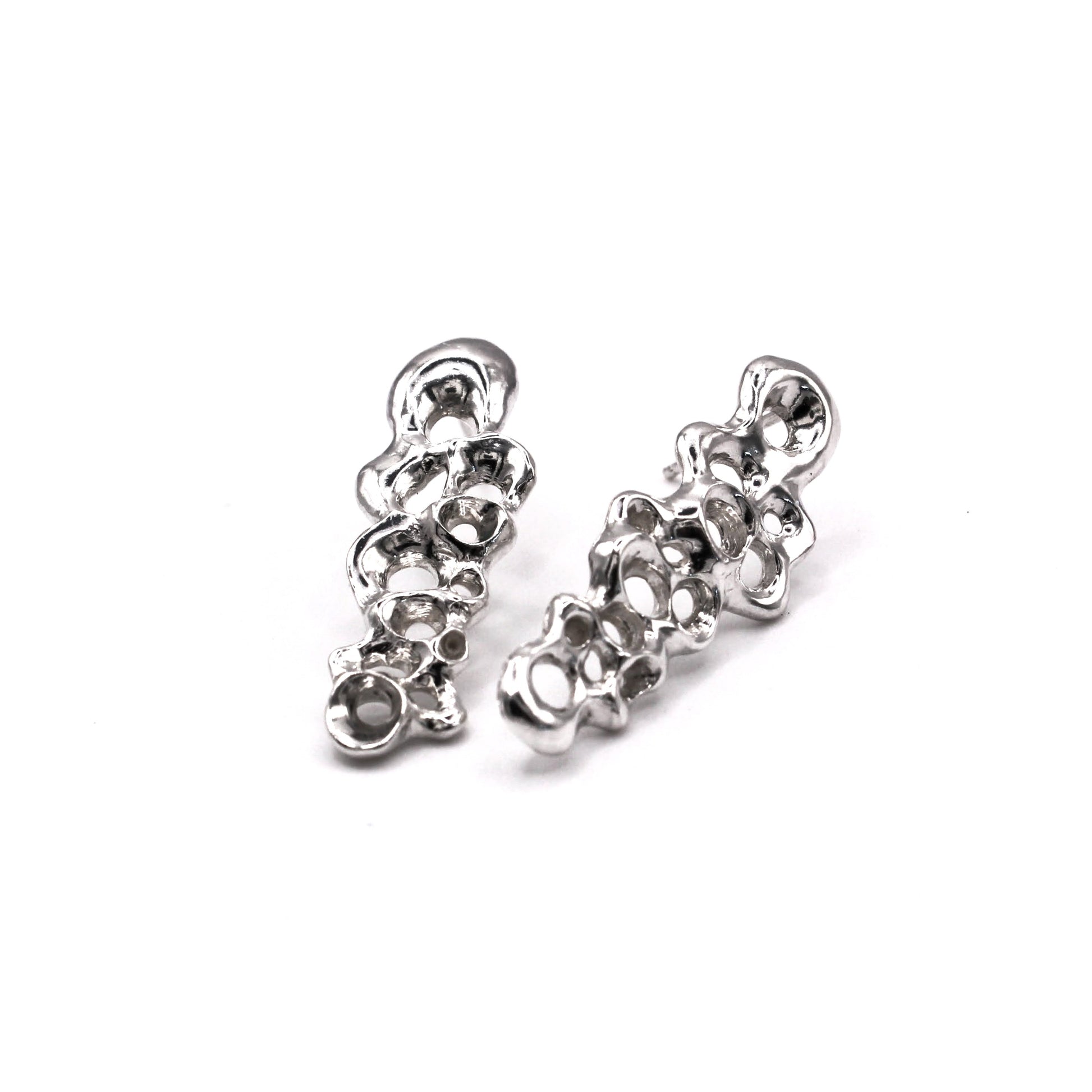 Pair of silver earrings on a white background. Pendientes largos Raíz en plata reciclada 925, pendientes asimétricos inspirados en bellotas del mar de Naturalesa Jewelry.