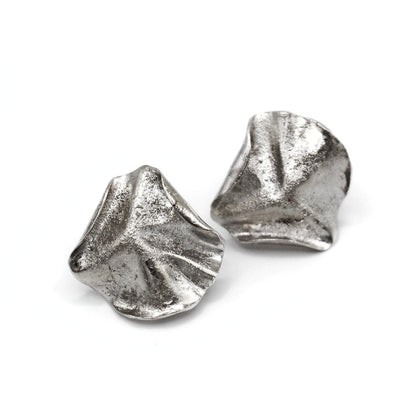 Sculptural folded silver earrings, handcrafted in recycled sterling silver using the lost wax casting technique. Mediterranean-inspired jewelry with organic, wave-like forms and a unique fused silver dust texture. Elegant and sustainable statement earrings for nature and contemporary jewelry lovers, crafted by Naturalesa.